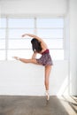 Young dancer woman stretches herself near window Royalty Free Stock Photo