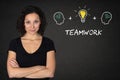 Young woman with crossed arms, heads thinking, lightbulb-idea and text `Teamwork` on a blackboard background. Royalty Free Stock Photo