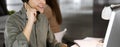 Young dark-haired guy in a green shirt and headsets is talking to a client, while sitting at the desk, working together Royalty Free Stock Photo