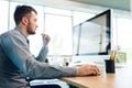 Young dark-haired man in blue shirt is working with computer at table in office. Focus on his hand with mouse Royalty Free Stock Photo