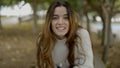 Young dark-haired woman in park smiles into camera, close slomo