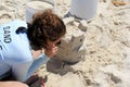 Young woman teaching beach visitors how to create sandcastles at the shore, Sand Castle University, Alabama, 2018