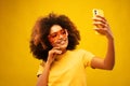 Young dark skinned happy mulatto woman with Afro hairstyle, holds modern mobile phone in front of face Royalty Free Stock Photo