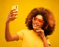 Young dark skinned happy mulatto woman with Afro hairstyle, holds modern mobile phone in front of face Royalty Free Stock Photo