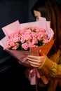 Young darkhair woman florist holding in hands large bouquet of fresh pink roses