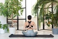 Young darkhair woman practicing yoga in the morning at her home near plants. The woman is engaged in self-determination