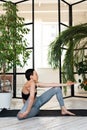Young darkhair woman practicing yoga in the morning at her home near plants. The woman is engaged in self-determination