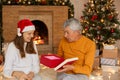 Young daughter gives her father Christmas gift, senior man with ted present box, being astonished and surprised, family posing Royalty Free Stock Photo