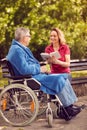 Daughter reading book outdoor her disabled father in wheelchair Royalty Free Stock Photo