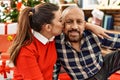 Young daughter and senior father together celebrating christmas at home, sitting by christmas tree around festive ornaments Royalty Free Stock Photo