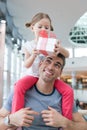 Young daughter sits on fathers shoulders and gives him a present Royalty Free Stock Photo