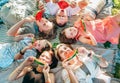 Young daughters with parents family lying on picnic blanket during weekend sunny day, smiling, laughing and eating red juicy Royalty Free Stock Photo