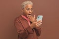 Young dazed ethnic African American woman holds phone and covers mouth with hand