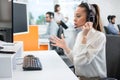 Young dedicated customer support representative woman talking with client using hands-free headset in call centre. Royalty Free Stock Photo