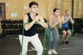 Motivated young man practicing exercises with stretch rope standing near other people in gym Royalty Free Stock Photo
