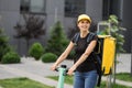 A young delivery girl with a yellow bag on her back rides an electric scooter down the street early in the morning.