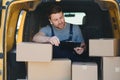 young delivery man courier in uniform hold documents clipboard checking list parcel post boxes near a car for service Royalty Free Stock Photo