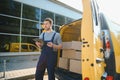 young delivery man courier in uniform hold documents clipboard checking list parcel post boxes near a car for service Royalty Free Stock Photo