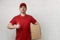 Young delivery man in red uniform standing with parcel box Royalty Free Stock Photo