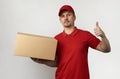 Young delivery man in red uniform standing with parcel box Royalty Free Stock Photo