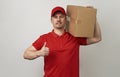 Young delivery man in red uniform standing with parcel box Royalty Free Stock Photo