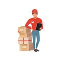 Young delivery man standing near stack of cardboard boxes with clip board in hand. Cartoon courier character in red cap Royalty Free Stock Photo