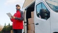 Young delivery man using tablet to find the address and deliver parcel