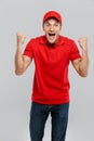 Young delivery man wearing uniform screaming while making winner gesture Royalty Free Stock Photo