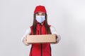 Young delivery woman in medical mask holding and carrying a cardbox isolated on white background. Buy food online in quarantine