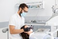 Dentist doctor in glasses filling teeth to female patient Royalty Free Stock Photo