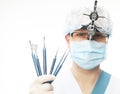 Young dentist male in white lab coat and mask holding dental instruments