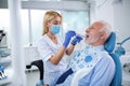 Young dentist examining teeth of an elderly patient