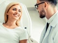 Young dentist talks with patient in dental clinic.