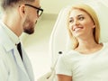 Young dentist talks with patient in dental clinic.