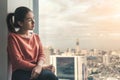 Young depressed asian woman sitting alone near window in dark at evening time with low light environment, PTSD Mental health