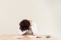 Young, depressed Caucasian freelancer man sitting in his home office at the table in front of empty clear wall. Royalty Free Stock Photo