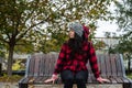 Young depressed homeless girl or woman with hat sitting alone on the bench on the street in the cold weather feeling desperate and Royalty Free Stock Photo