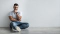Young depressed man sit against gray wall at home feeling unhappy, lonely and sad in depression Royalty Free Stock Photo