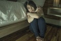 Young depressed and sad Asian Korean woman sitting on floor at bedroom next to bed suffering depression problem and anxiety crisis