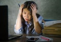 Young depressed and stressed Asian Chinese student girl working with laptop and book pile overwhelmed and frustrated preparing exa Royalty Free Stock Photo