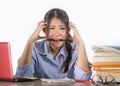 Young depressed and stressed Asian Chinese student girl working with laptop and book pile overwhelmed and frustrated preparing Royalty Free Stock Photo