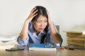 Young depressed and stressed Asian Korean student girl working with laptop and book pile overwhelmed and frustrated preparing exam Royalty Free Stock Photo