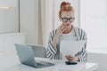 Young depressed woman with having financial problems, sitting at table with laptop and calculator Royalty Free Stock Photo