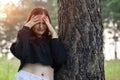 A young depressed woman is sad by a tree in Park. The girl is crying with her head in her hands Royalty Free Stock Photo