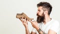 Young designer holding a wooden last shoe on white background. Creative idea of new shoes model. Serious young cobbler sets up