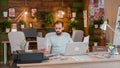 Young designer looking at a sheet in her hand while working on the laptop Royalty Free Stock Photo