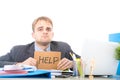 Young desperate businessman holding help sign looking worried suffering work stress at computer desk Royalty Free Stock Photo