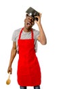 Young desperate and confused black afro american man in chef apron holding cooking pot in his head