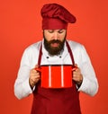 Young desperate and confused man in chef apron holding pot