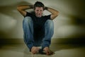 Young desperate and depressed man crying alone sitting at home floor in shady and dramatic studio light looking sad and frustrated Royalty Free Stock Photo